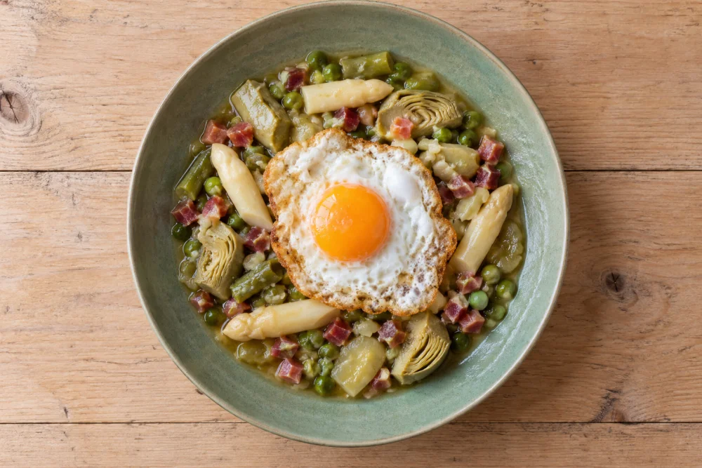 Menestra de verduras con yemas esparrago, huevo frito y taquitos de jamon.